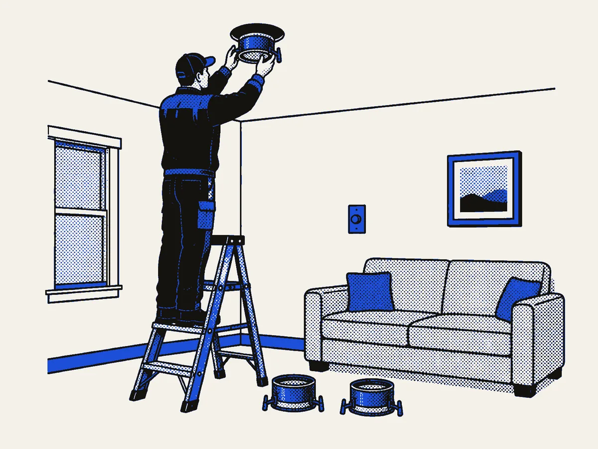 Electrician on a ladder fitting a recessed light in a living room